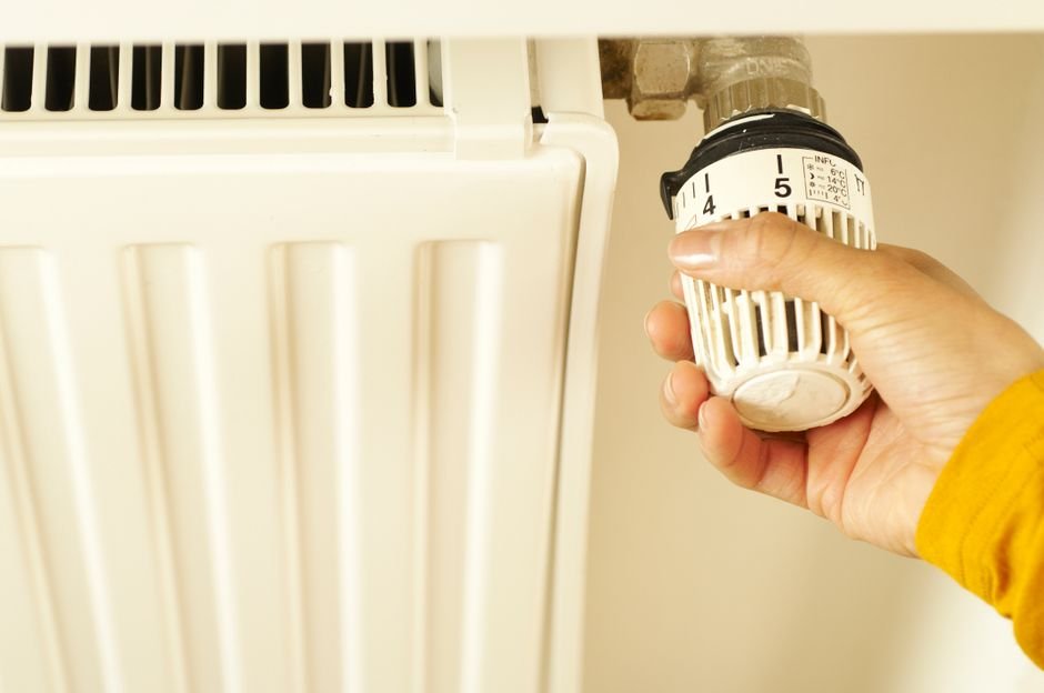 Hand adjusting a radiator valve, a heating system that can take 30 minutes to warm up