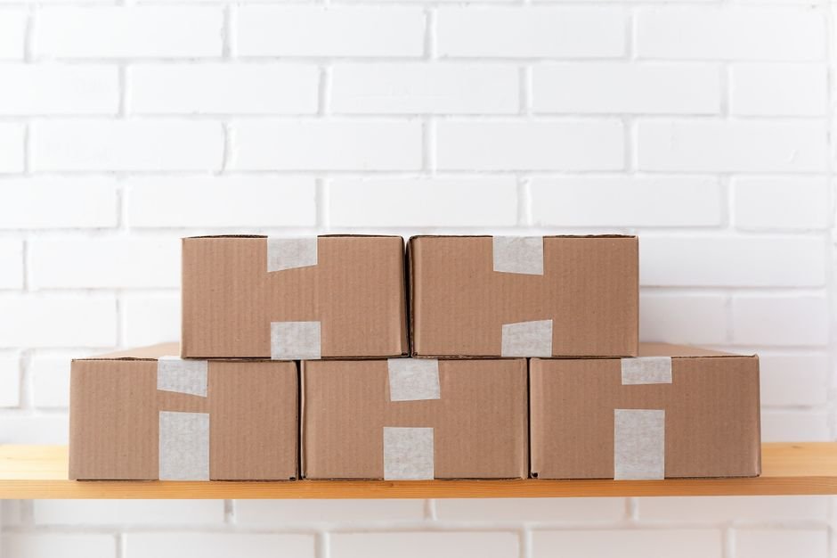 Taped cardboard boxes stored on a wooden shelf, like sealed sets held for resale