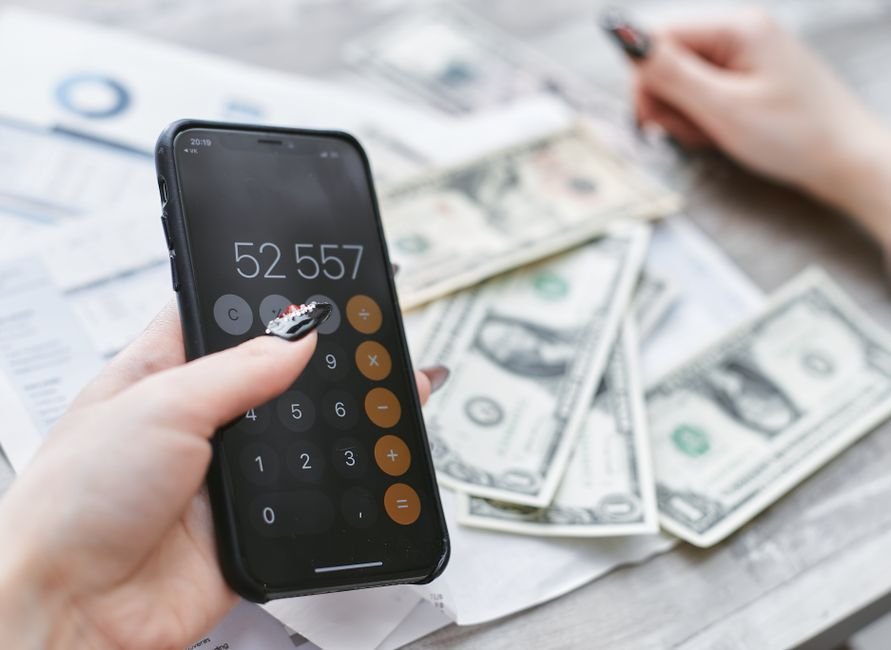 Phone calculator next to dollar bills, used to work out the yearly cost of a streaming subscription