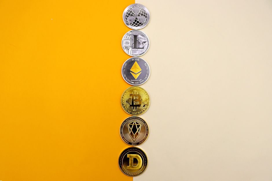 Row of cryptocurrency coins on a yellow surface