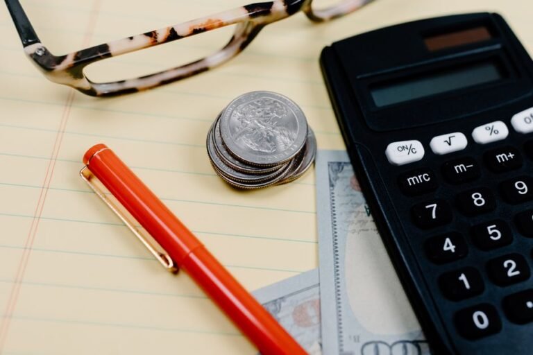 Calculator, coins and glasses on a notepad on a desk