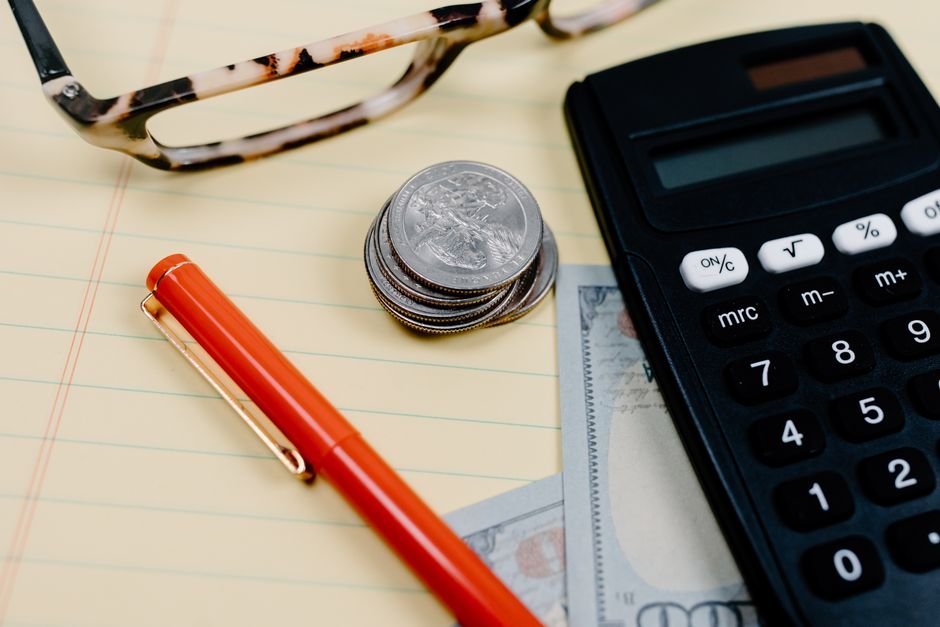 Calculator, coins and glasses on a notepad on a desk
