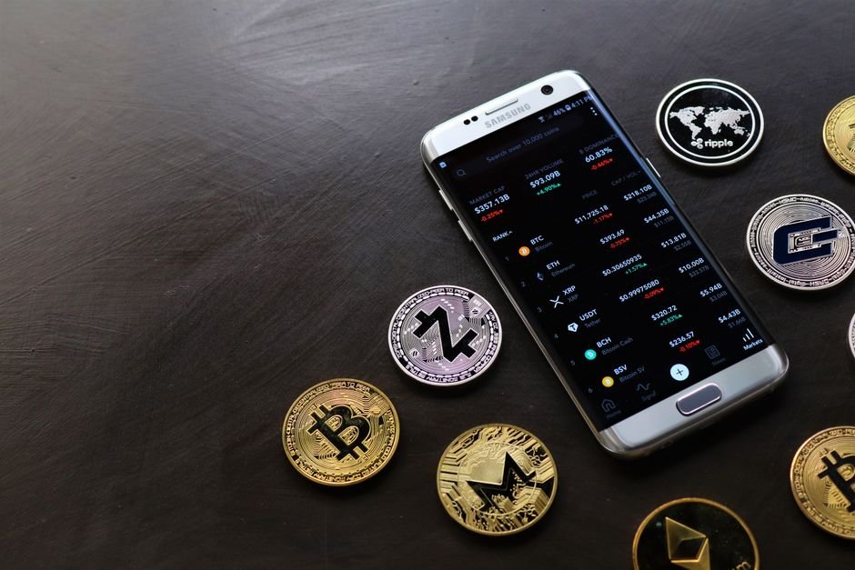Smartphone showing a crypto app next to coins