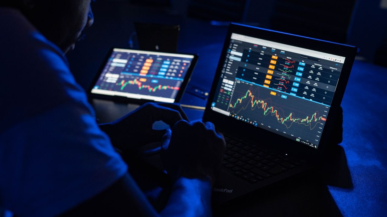 Trader watching charts on laptops in a dim room, the typical weekend stock perpetual setup